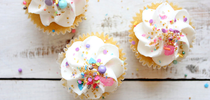 Three cupcakes with white icing and sprinkles
