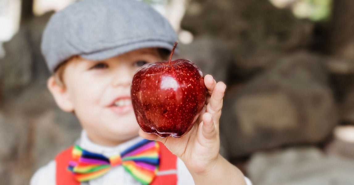 Small child with a bow tie on holding an apple