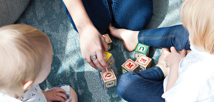Two kids and a woman playing with blocks