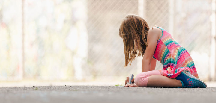 Girl playing with chalk on the pavement