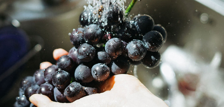 A bunch of grapes being washed in a sink