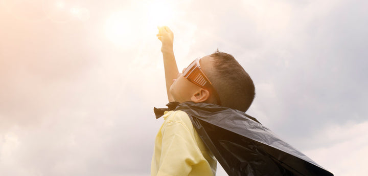 Kid with cape reaching to the sky