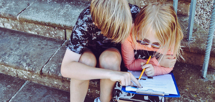 Two kids answering questions on a white piece of paper