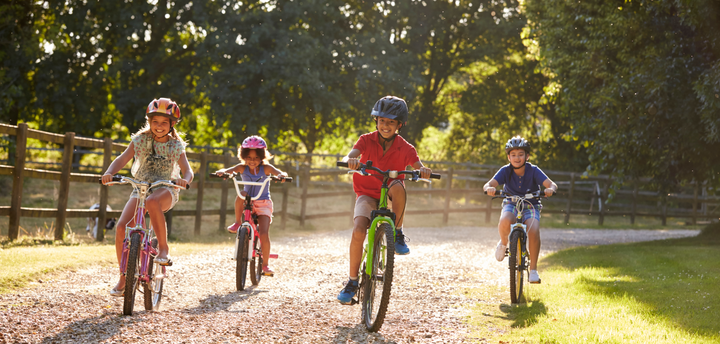 Four kids riding bikes on a dirt road