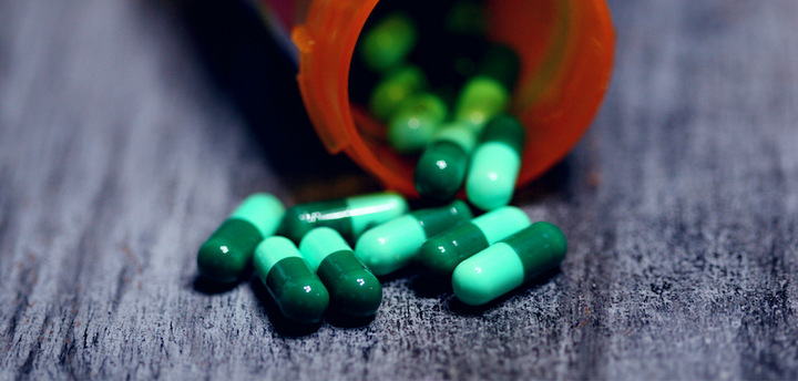 Pills falling out of a prescription bottle onto a table