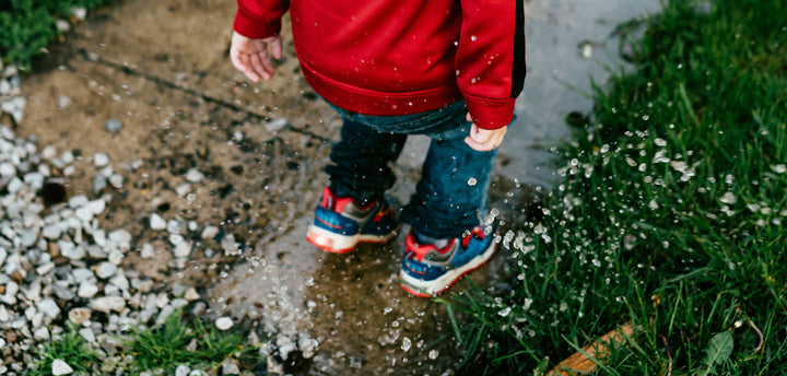 Little boy jumping in a puddle