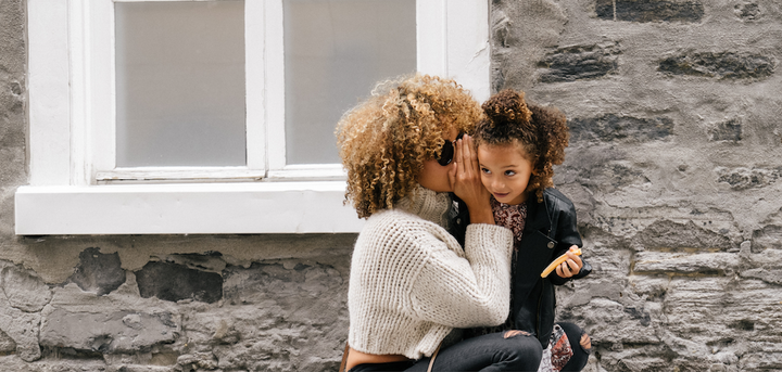 Woman whispering into a child's ear
