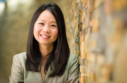 Headshot of Dr. Julie Wei leaning against a brown brick wall