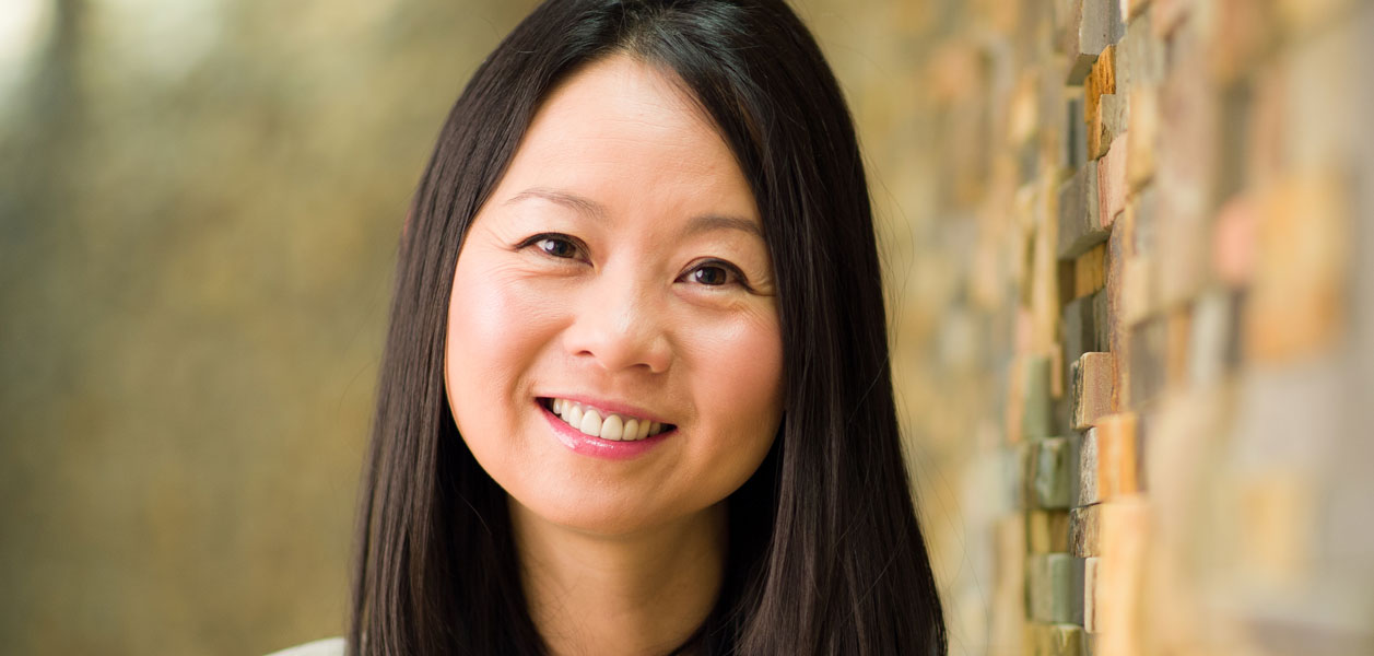 Headshot of Dr. Julie Wei leaning against a brown brick wall