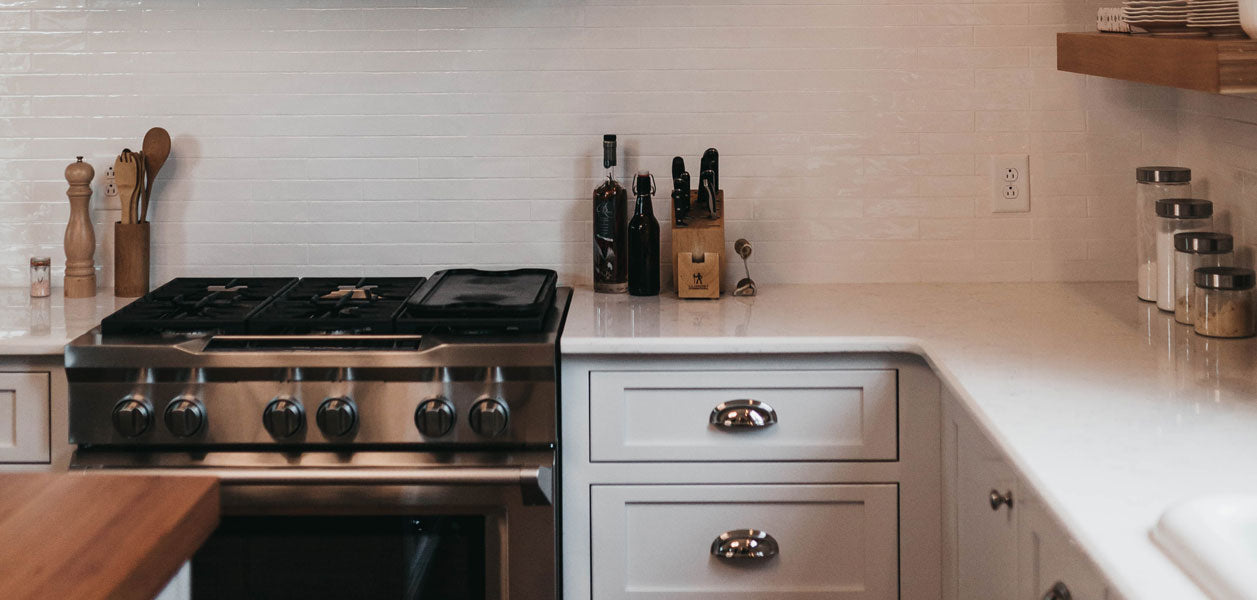 Clean white kitchen with a stainless steel stove and wooden island