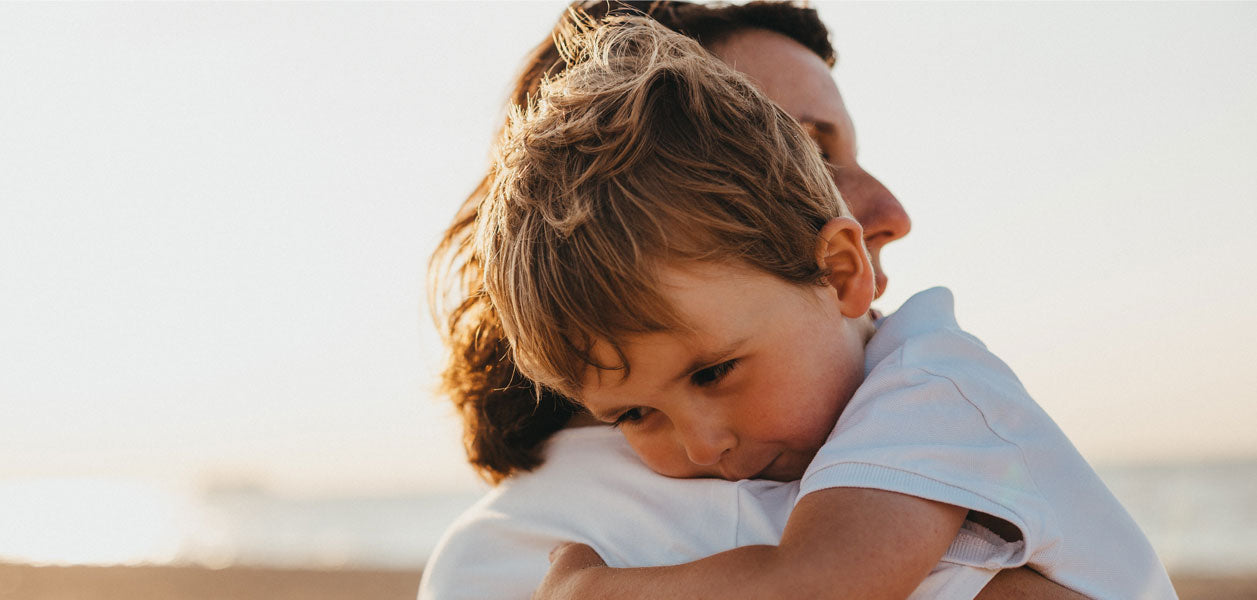 Woman holding a little boy outside on a beach