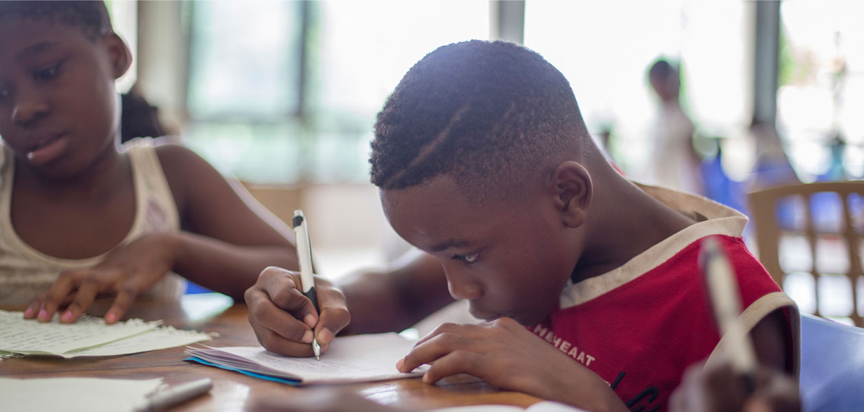 A boy and a girl sitting at a table writing in a notebook